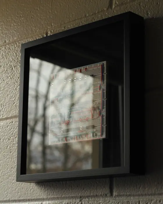The Logic Frame hanging on a wall behind glass, for a sense of size